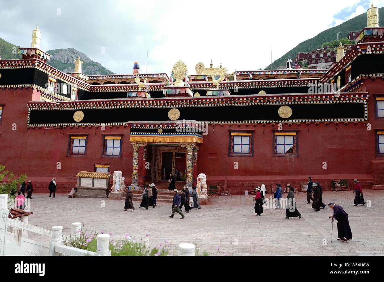 Les Tibétains locaux et touristes passent devant la maison Sutra-Printing Dege, ou Dege Parkhang les écritures anciennes maison d'impression à l'intérieur de l'Gengqing Monas Banque D'Images