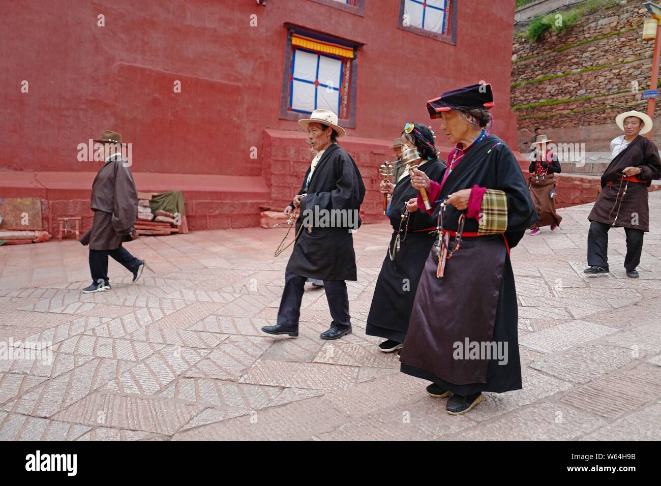 Les tibétains de tourner les roues de prière devant la maison Sutra-Printing Dege, ou Dege Parkhang les écritures anciennes maison d'impression à l'intérieur de l'Geng Banque D'Images