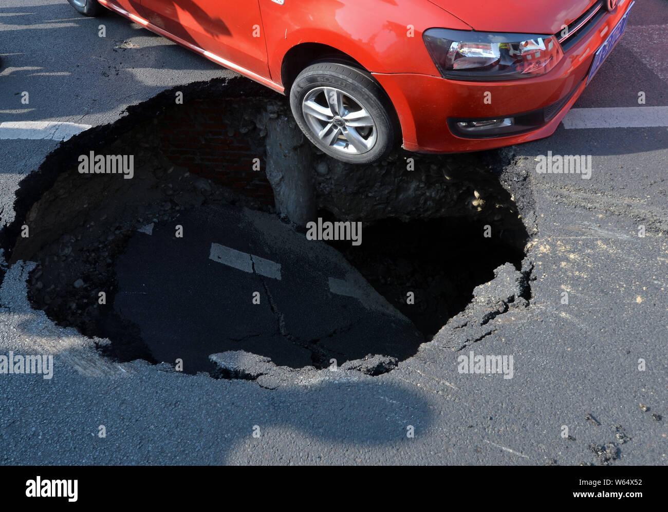 Un véhicule est pris au piège dans un gouffre après l'effondrement d'une route dans la ville de Chengdu, dans le sud-ouest de la province chinoise du Sichuan, le 15 août 2018. Un gouffre qui est al Banque D'Images