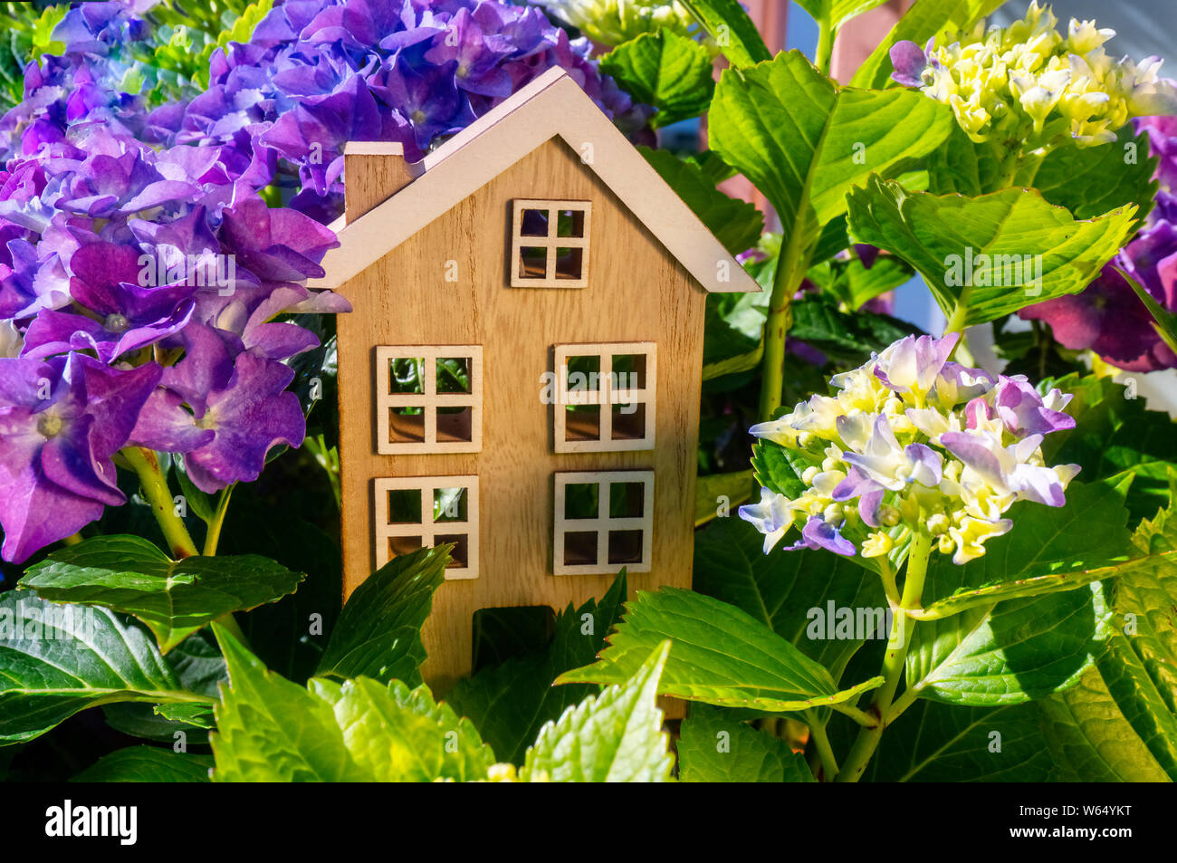 Maison en bois se tient entre les fleurs et les feuilles Banque D'Images