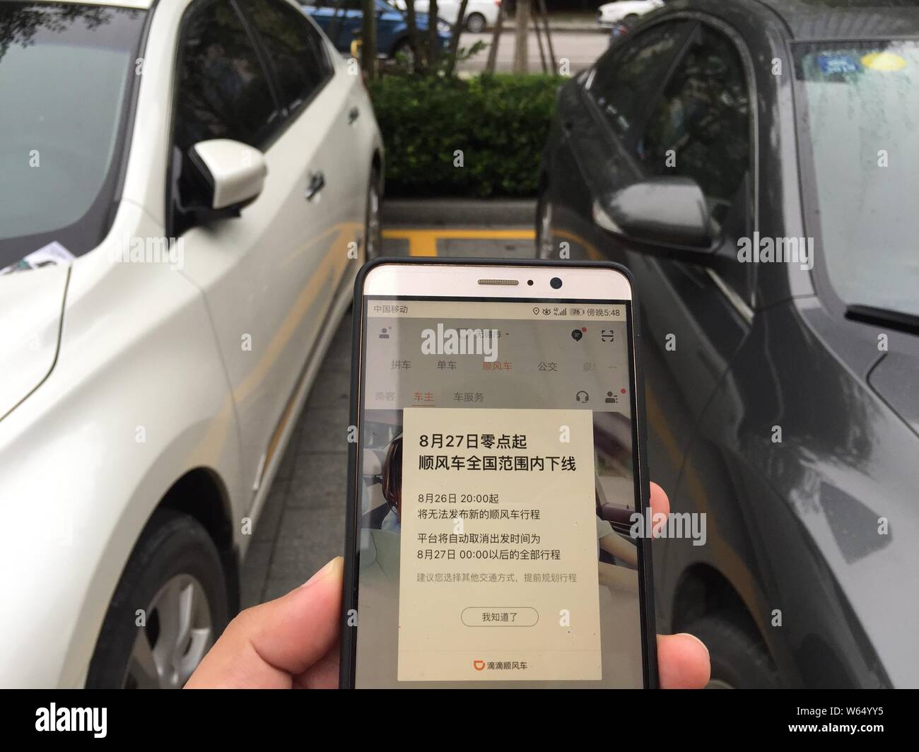 Un résident chinois ressemble à une annonce montrant l'attelage de covoiturage de taxi-originaire et un service de voiture Didi Chuxing d'être stoppée nationwi Banque D'Images