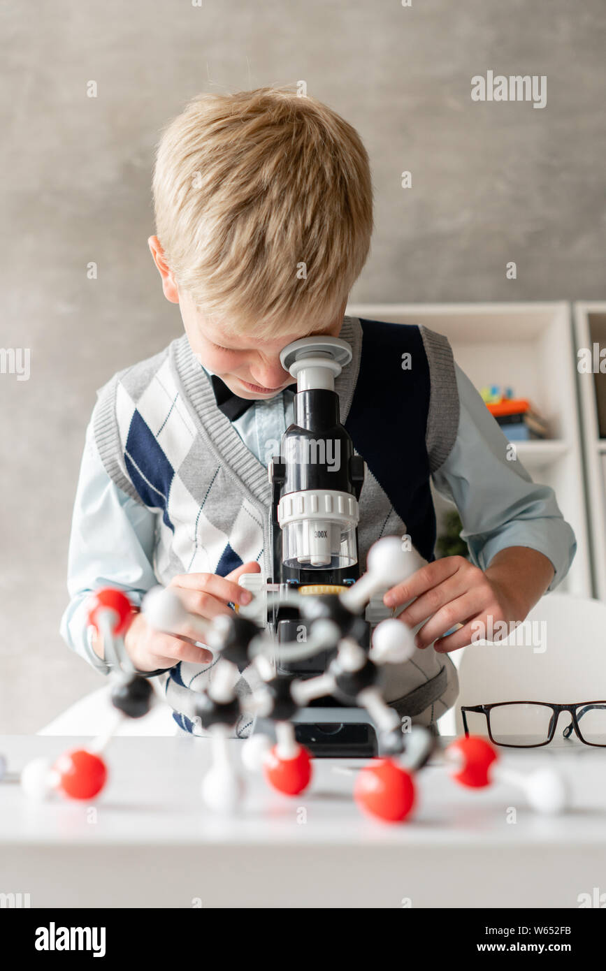 Petit écolier dans les tenues de l'air en microscope Banque D'Images