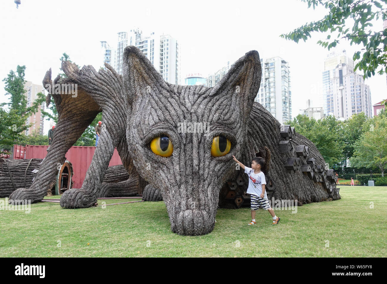 Un jeune garçon caresse la tête de la haute- 7 mètres et 10 mètres de long et paille de métal sculpture 'Fox' urbain après qu'il est démantelé à la Sculpture de Jing'an Banque D'Images