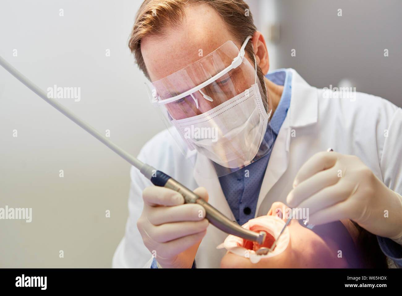 Dentiste avec masque de protection se concentre dans le traitement avec le foret dans la clinique dentaire Banque D'Images