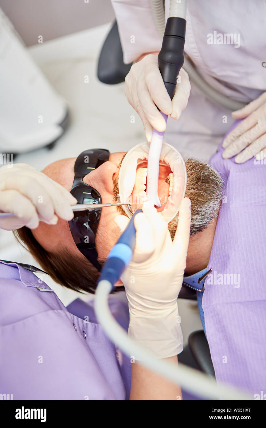 Dentiste avec foret supprime le tartre ou la carie dentaire au cours d'un traitement au cabinet dentaire Banque D'Images