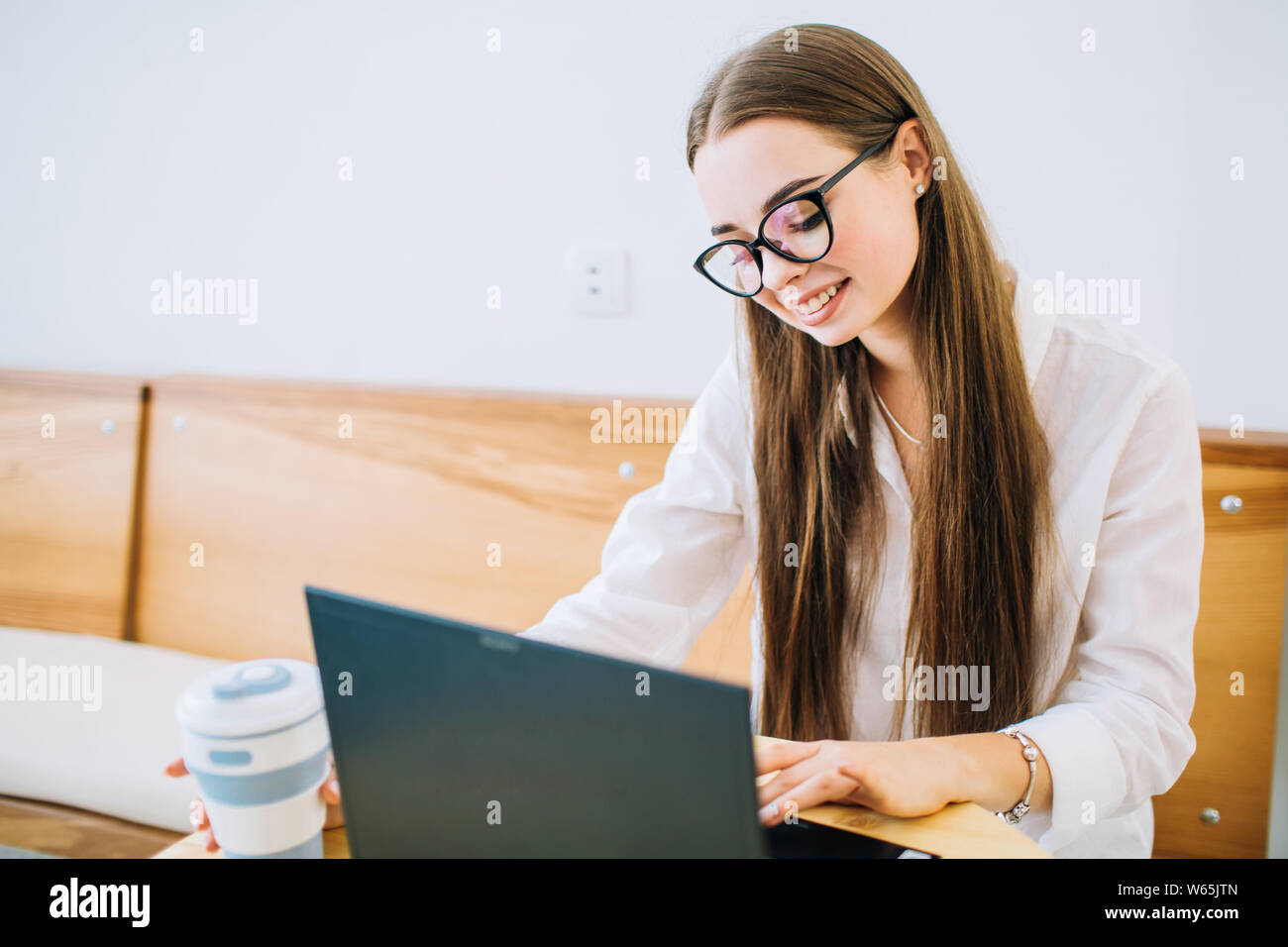 Photo de young happy woman using laptop while sitting at cafe, café potable.jeune fille assise dans un café et travailler sur ordinateur portable. Banque D'Images