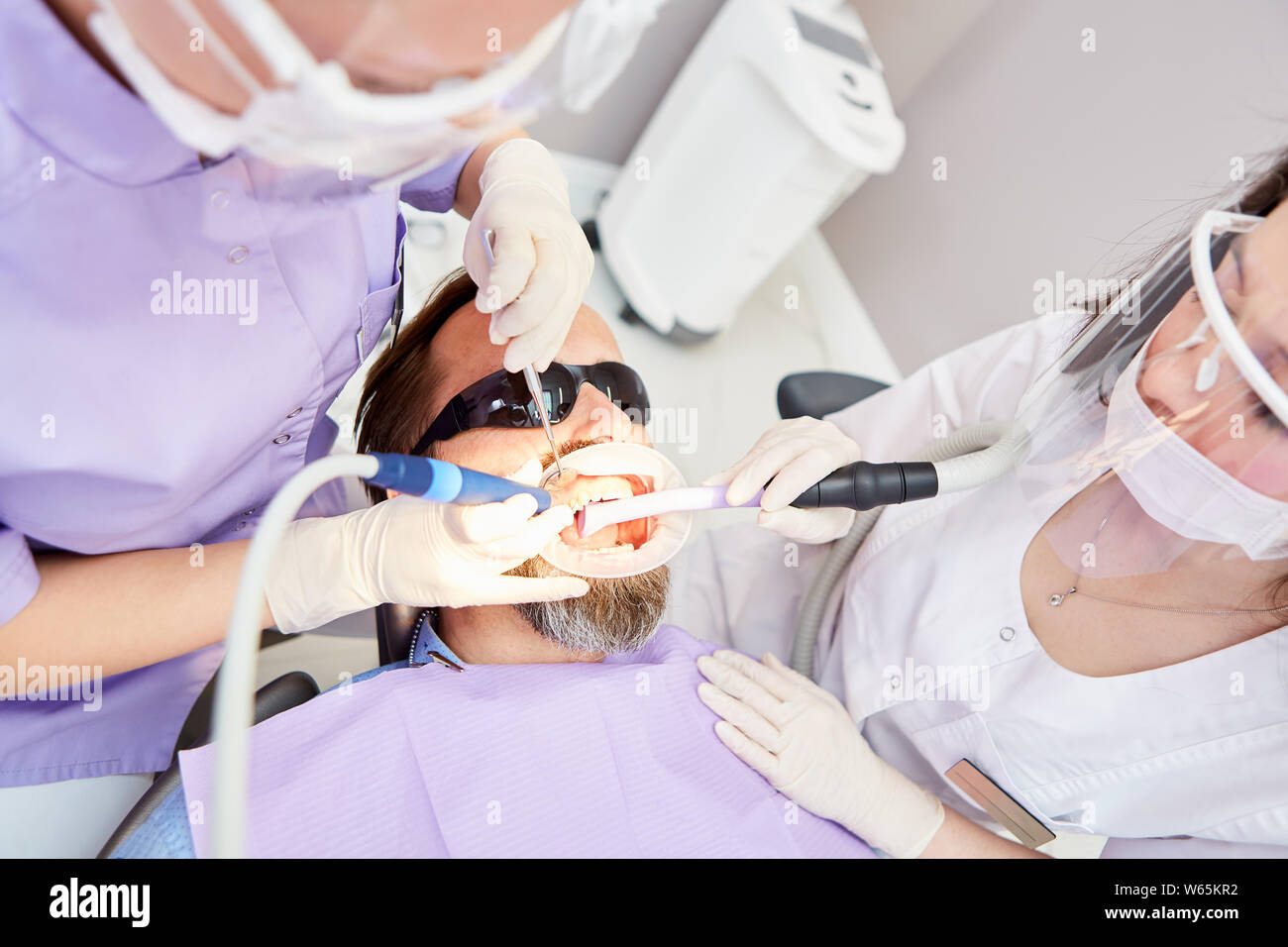 Dentiste et l'assistant dans le traitement d'un patient avec une perceuse dans la clinique dentaire Banque D'Images