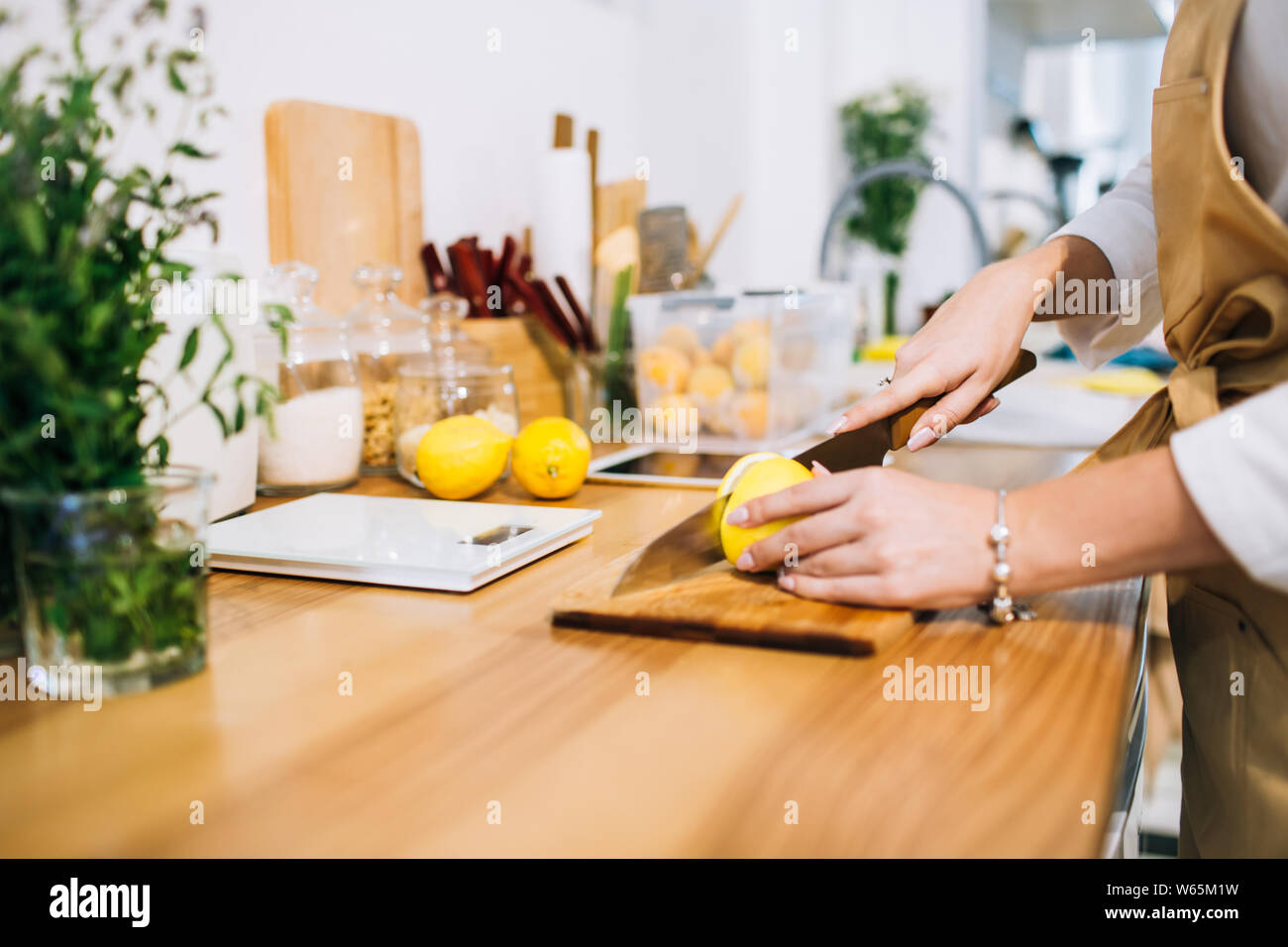 Les mains de citron coupe avec un couteau bien aiguisé dans une cuisine minimaliste lumineux, se préparer pour la cuisson. Banque D'Images
