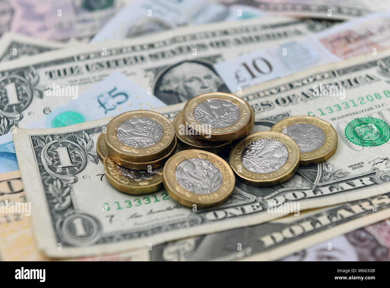 United States dollar bills entre UK Pound sterling pièces de monnaie et billets de banque. Banque D'Images