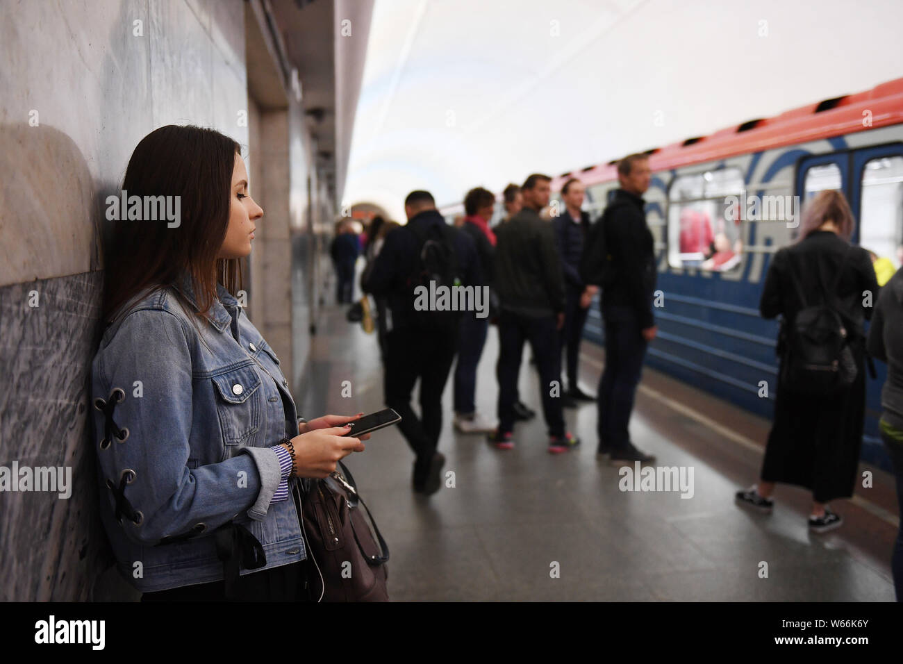 Un frontalier utilise son smartphone alors qu'elle attend une rame de métro dans une station de métro de Moscou à Moscou, Russie, le 4 juillet 2018. Le métro de Moscou est Banque D'Images Un frontalier utilise son smartphone alors qu'elle attend une rame de métro dans une station de métro de Moscou à Moscou, Russie, le 4 juillet 2018. Le métro de Moscou est Banque D'Images