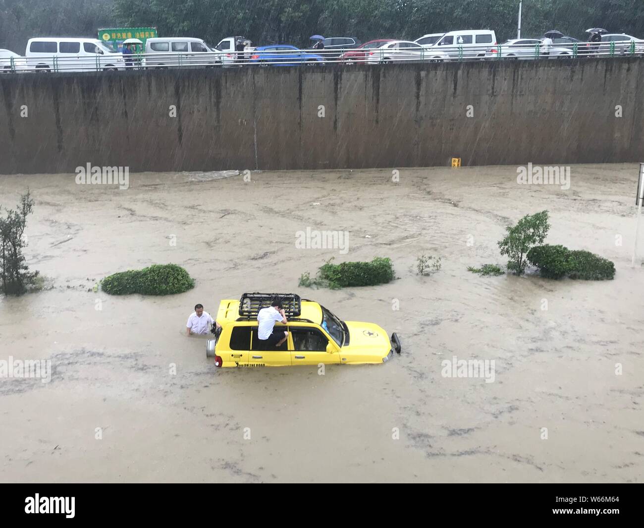 Les résidents de pousser une voiture piégée dans une route inondée causées par de fortes pluies dans la ville de Chengdu, dans le sud-ouest de la province chinoise du Sichuan, le 11 juillet 2018. Fl Banque D'Images