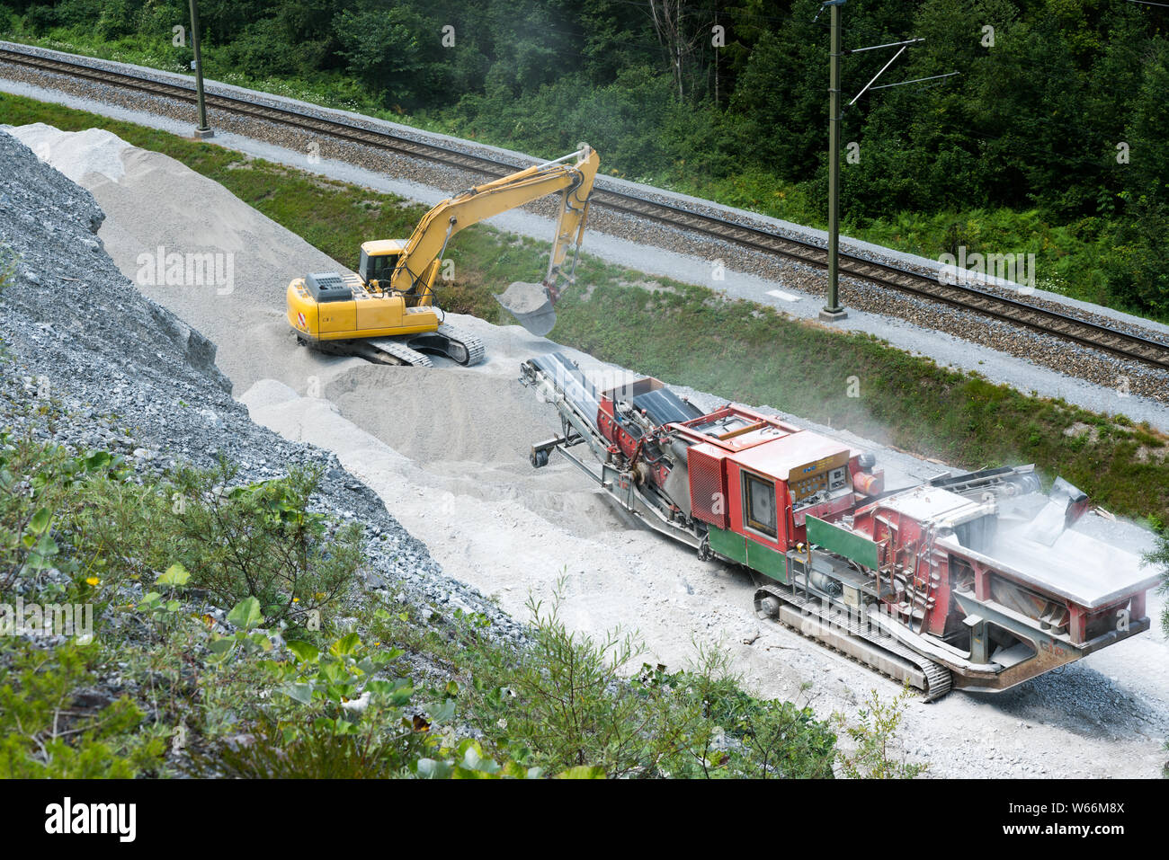 Versam, GR / Suisse - 30. Juillet 2019 : rock et de l'excavateur de meuleuse pour produire une bonne qualité de cailloux de grosses roches à côté des voies de chemin de fer Banque D'Images