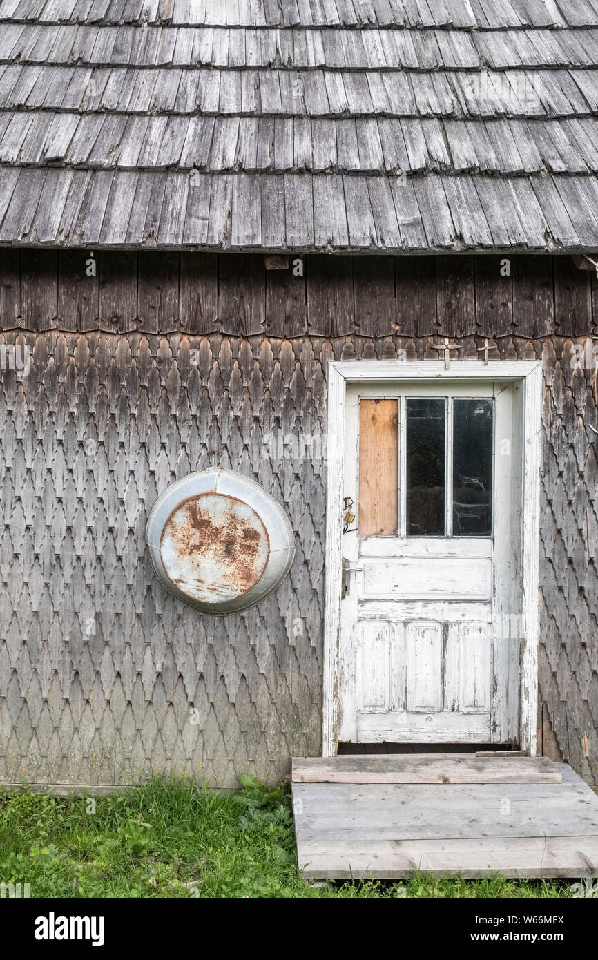 Une ancienne ferme typique en Bucovine, Roumanie. Toit et murs sont revêtus de bardeaux de bois, avec des crucifix sur la porte Banque D'Images