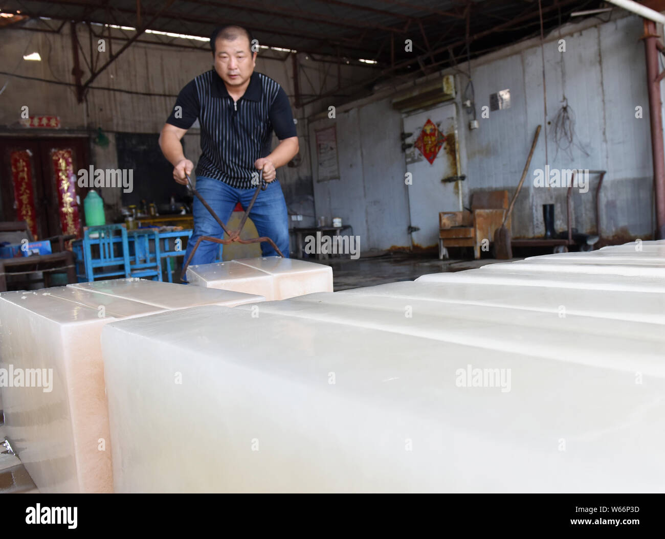 Un processus de travail chinois de blocs de glace dans une fabrique de glace dans la ville de Chaohu, Chine de l'est l'Anhui province, 22 juillet 2018. Les travailleurs chinois chargés de blocs de glace Banque D'Images