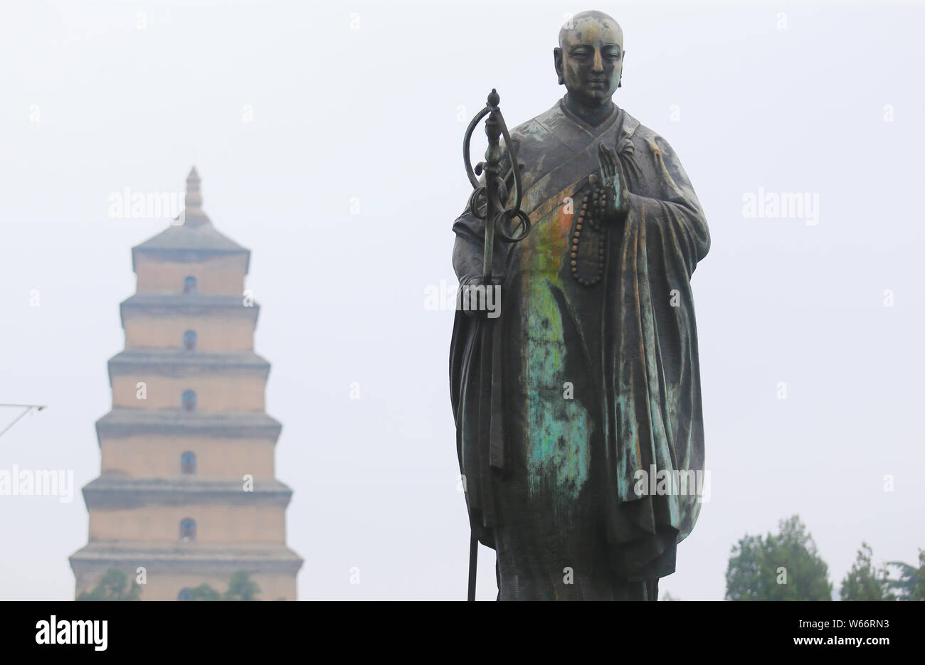 Une statue de bronze de moine bouddhiste chinois Xuanzang se colorer de vert s'affiche en face des Giant Wild Goose Pagoda ou la Grande Pagode de l'Oie Sauvage à Xi'an Banque D'Images