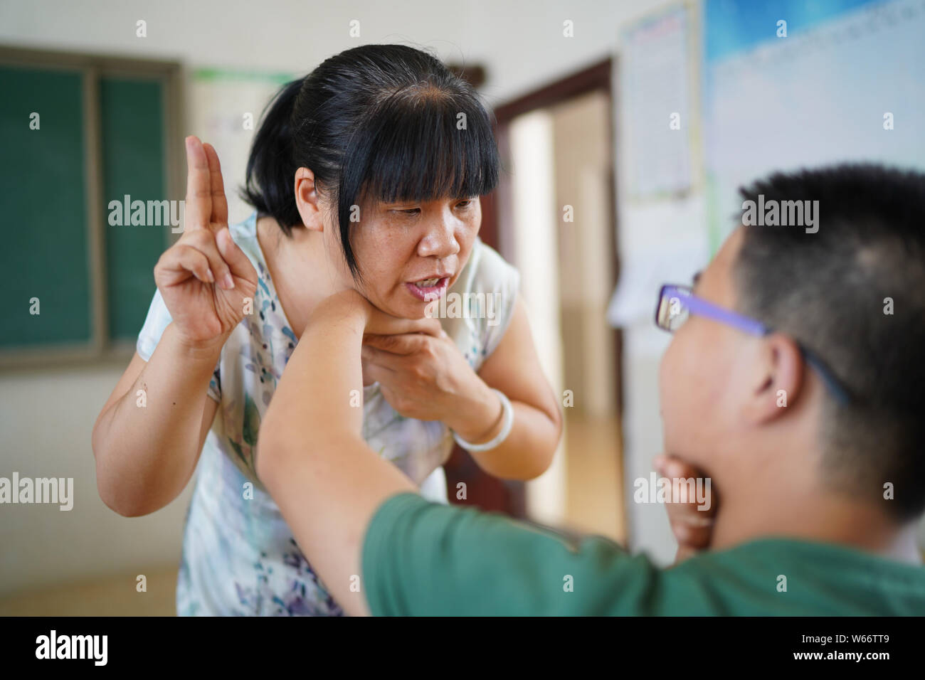 (190731) -- NANCHANG, 31 juillet 2019 (Xinhua) -- Liu Xiaoqing (L) met la main d'un élève sur sa gorge lors d'une formation de la voix et de la parole à l'École d'éducation spéciale Comté Luxi Luxi en comté de Pingxiang, la Chine de l'est la province, le 3 juillet 2019. Lorsque le comté de Luxi d'adaptation scolaire a été créé en 1997, Liu Xiaoqing, puis un diplôme universitaire normal, sollicité un poste là sans hésitation. Travailler comme professeur d'éducation spéciale a été difficile, comme les étudiants ont besoin de Liu beaucoup plus d'attention que leurs camarades sans handicap physique ou mental. Mais Liu est resté o Banque D'Images