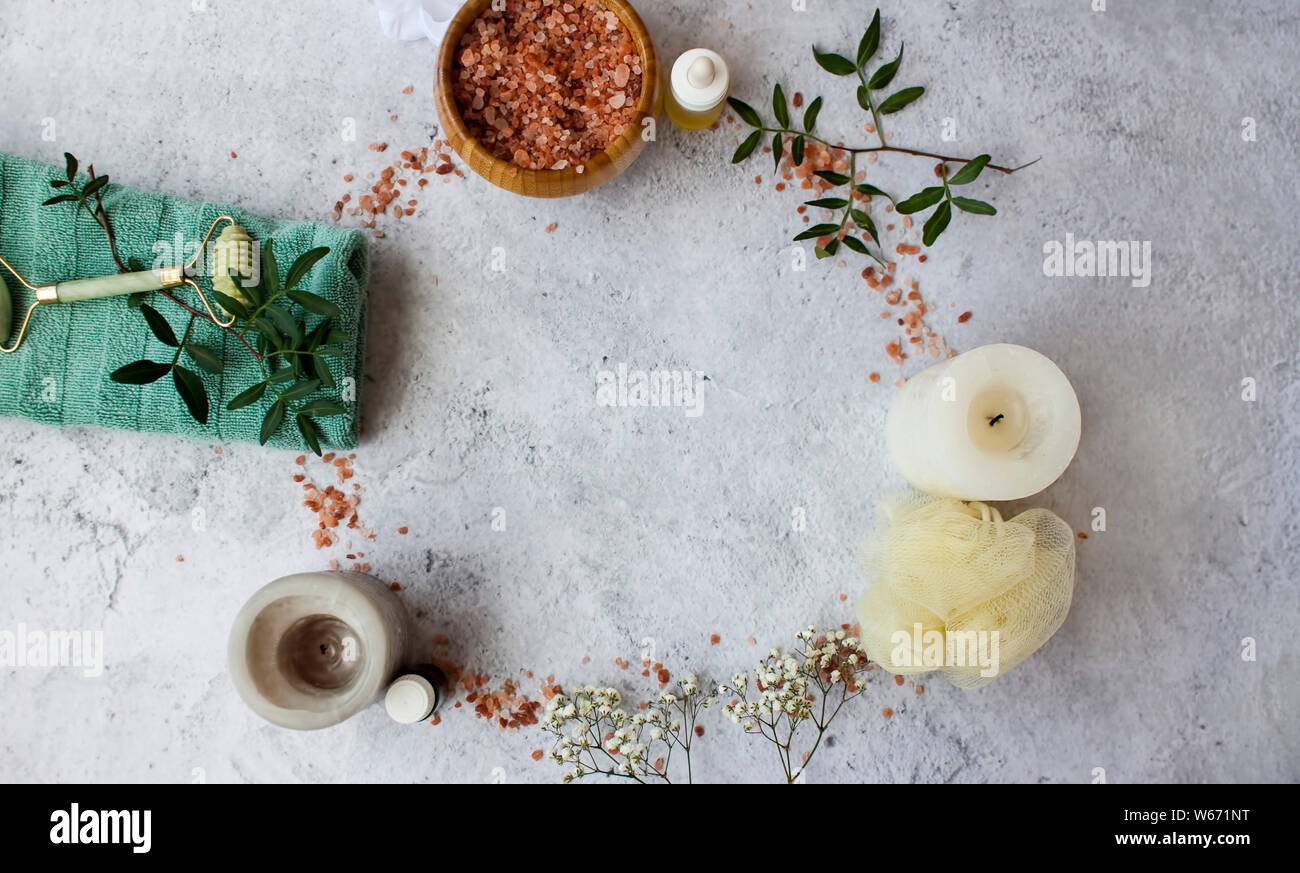 Spa de première nécessité comme le sels de bain, huiles essentielles, bougies, porte-serviettes et des fleurs pour un bain relaxant sur surface grise. Banque D'Images