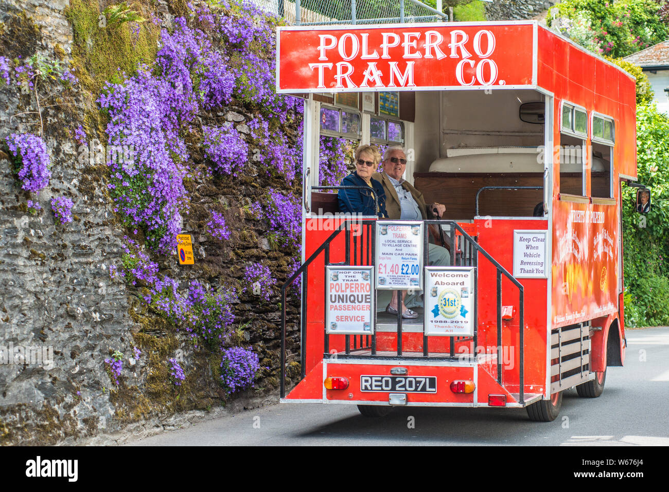 Red bus transportant les touristes pittoresque dans le village de caractère de Polperro à Cornwall, en Angleterre, Royaume-Uni Banque D'Images