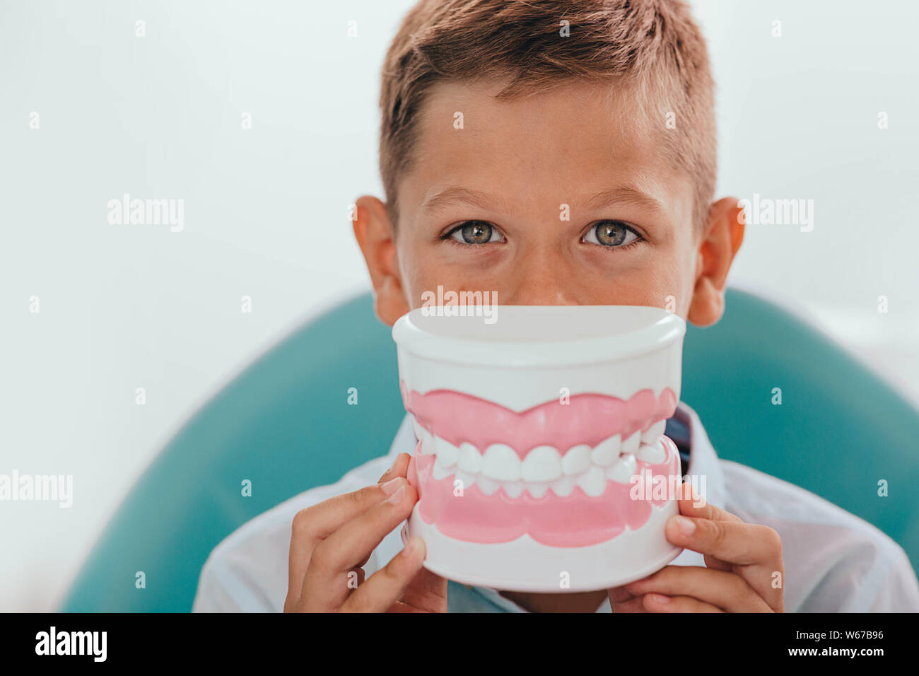 Cute boy modèle montrant des dents en face de sa bouche,selective focus sur les yeux. Publicité drôle de traitement des dents de l'enfant Banque D'Images