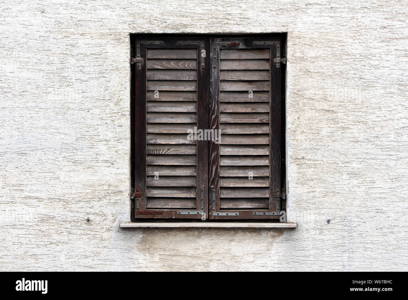 Fermé en bois délabrées des stores de couleur ternes avec charnières métalliques rouillées et montées sur mur sale maison familiale à l'ancienne partie de la ville Banque D'Images