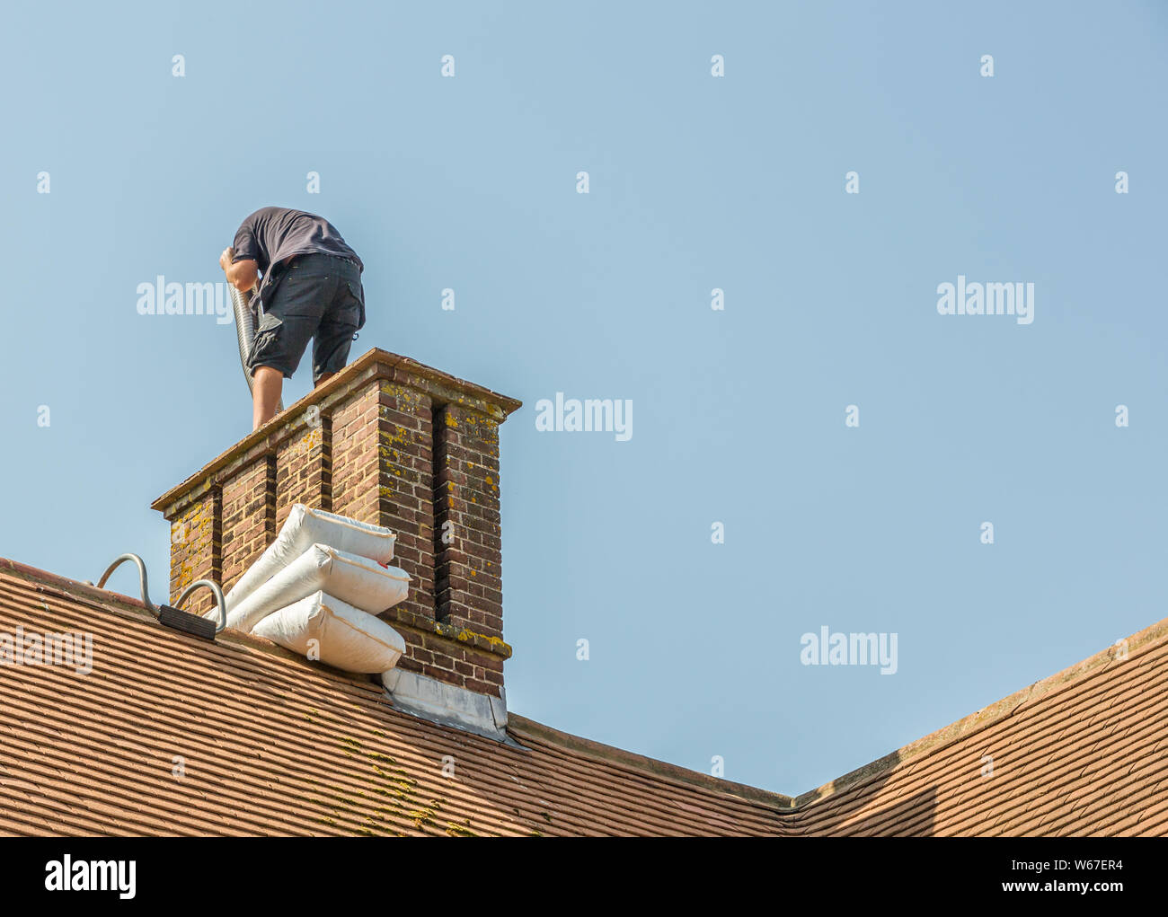 L'installation de cheminée sur une maison construite en 1930. Un installateur qualifié peut être vu en plaçant le tube métallique à l'intérieur de la cheminée à un haut le travail Banque D'Images