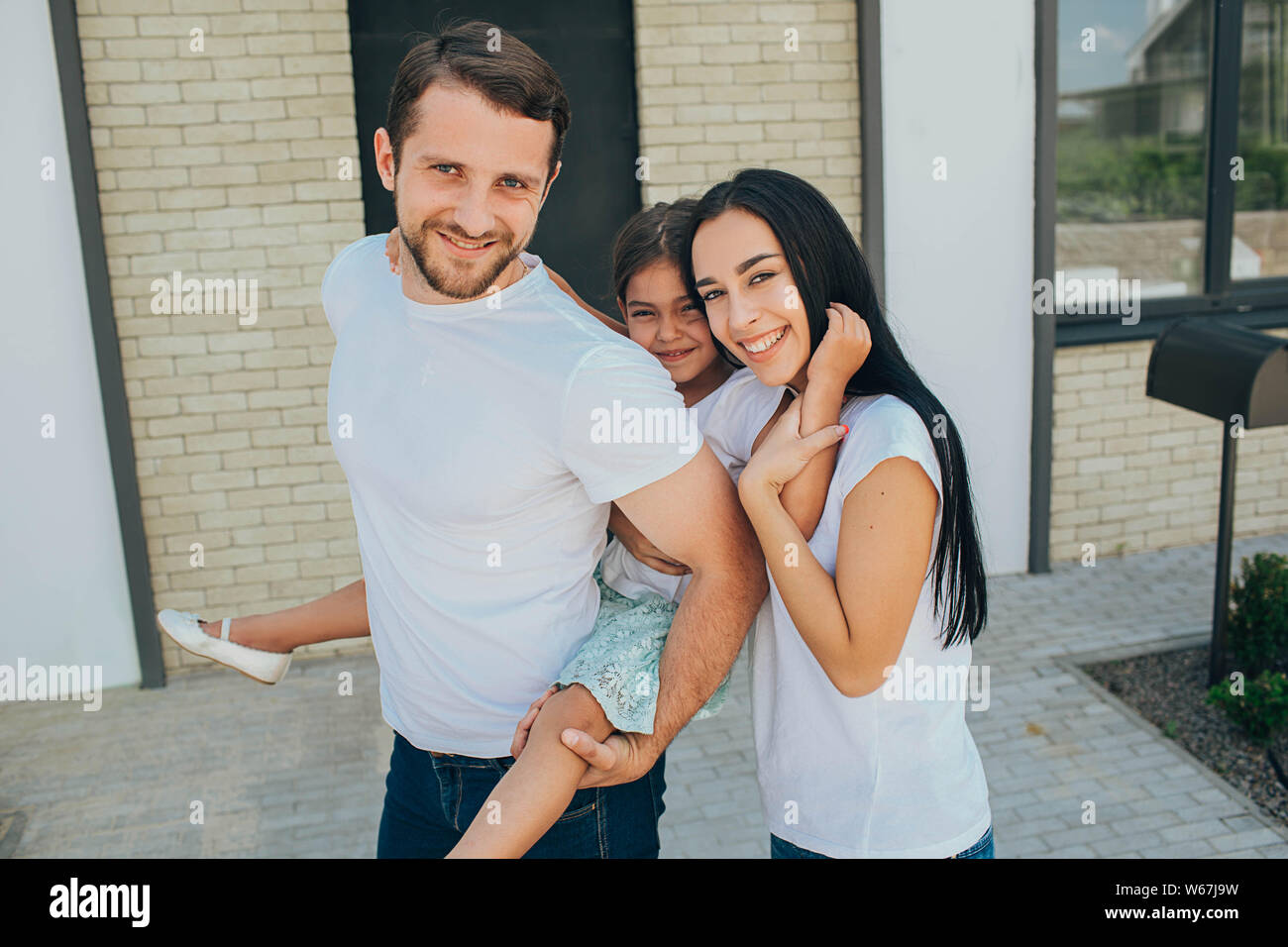 Fille sur un piggy back ride avec ses parents. Mère, père et fille ont un bon moment près de la chambre Banque D'Images