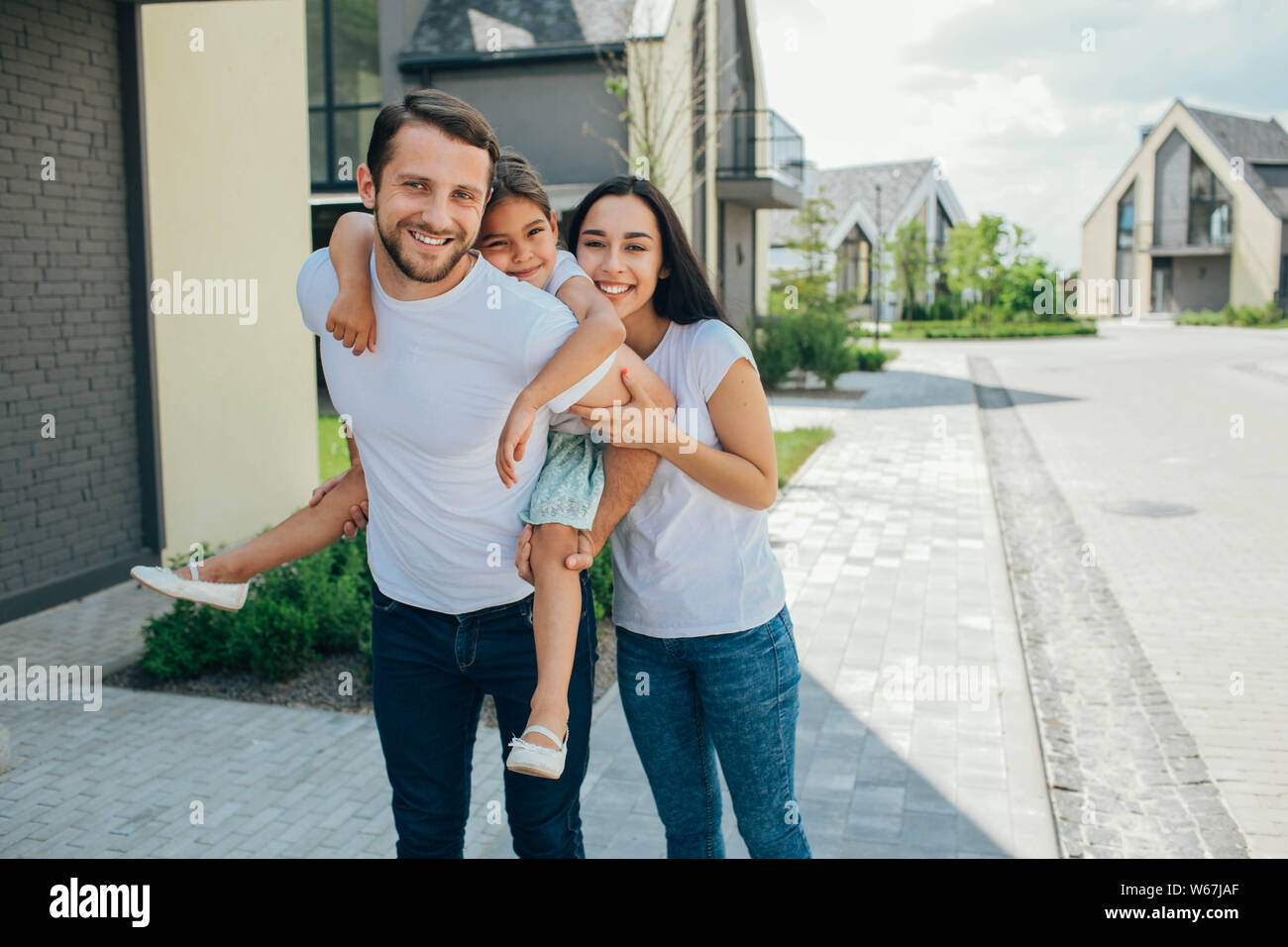 Fille sur un piggy back ride avec ses parents. Mère, père et fille ont un bon moment près de la chambre Banque D'Images