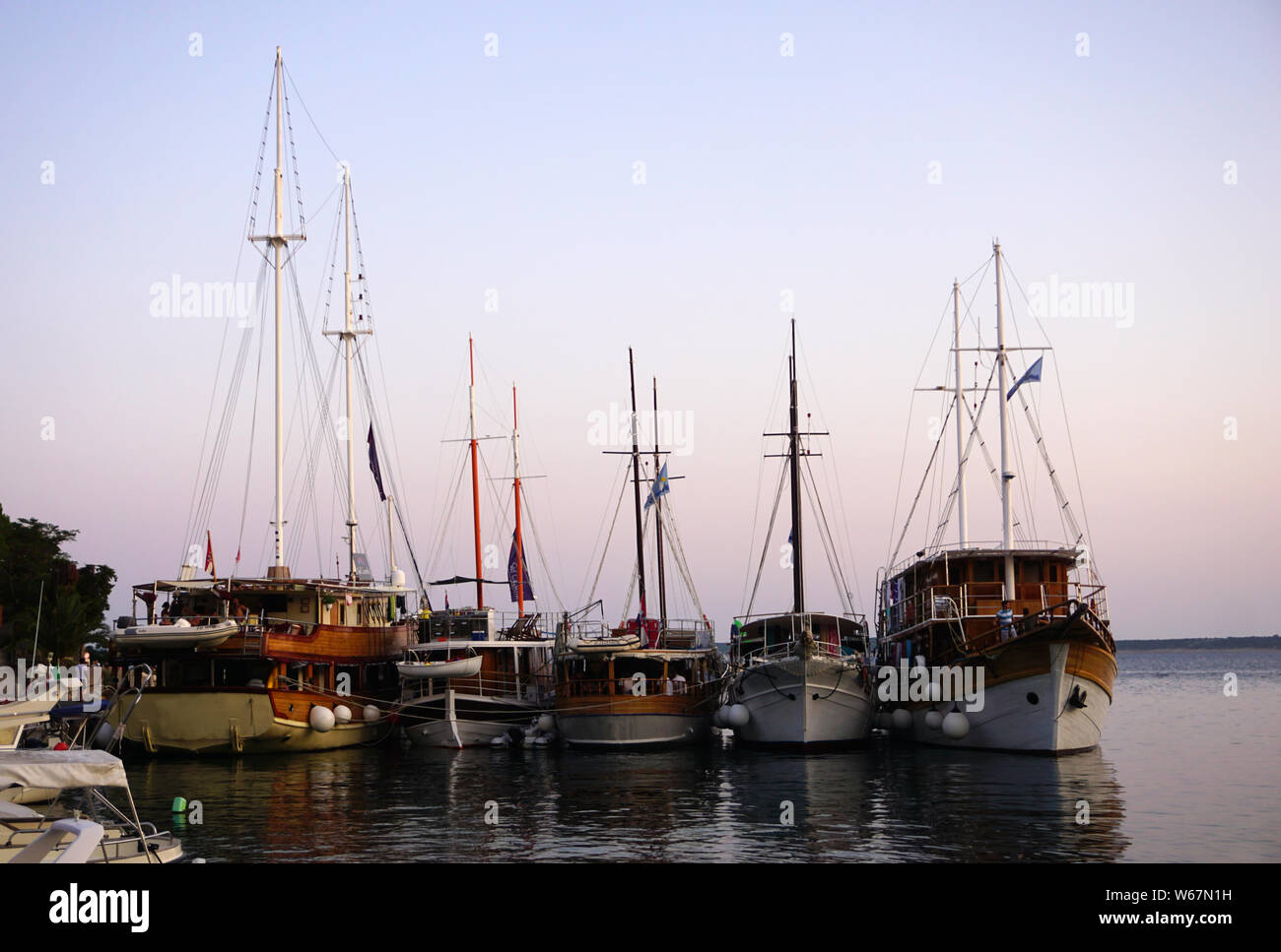 Mandre, île de Pag, Croatie, 29 juillet 2019. Les bateaux à voile touristique plein d'heureux touristes ancrés dans le port dans la soirée heure bleue Banque D'Images