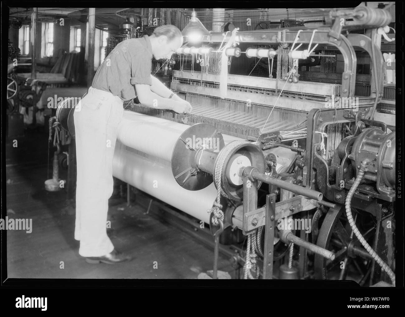 Paterson, New Jersey - Textiles. Wishnack Silk Company. Vue arrière de la même loom montrant le double faisceau. Un simple, double et triple faisceau est utilisé sur ce type de métier à tisser en fonction du type de fil et de tissu utilisé. Le chiffon illustré est un mélange d'un fils de rayonne et l'acétate d'un fils, les deux ayant besoin de différents prendre électriques ; D'où l'utilisation de la double faisceau. Banque D'Images