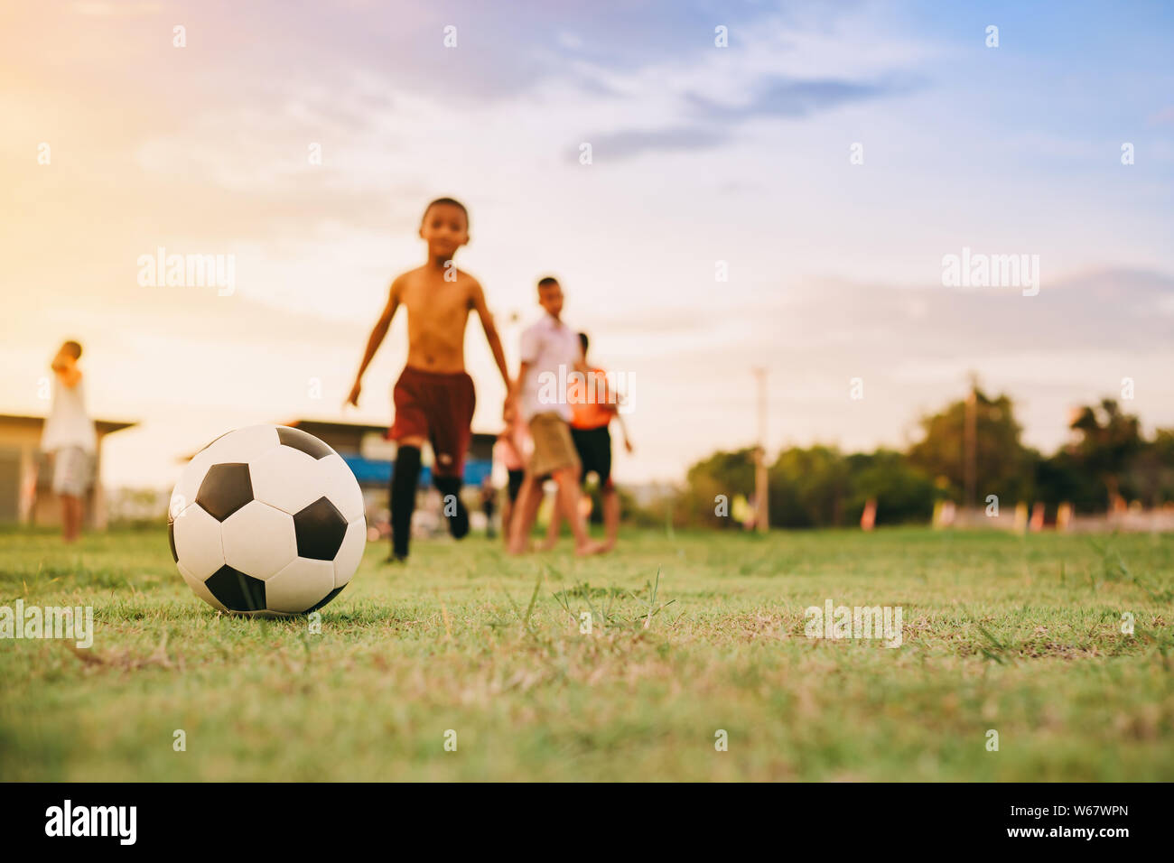 Le sport à l'extérieur de l'action d'un groupe d'enfants s'amusant à jouer au soccer le football pour faire de l'exercice en zone rurale communautaire . Pauvres et la pauvreté des enfants. Banque D'Images