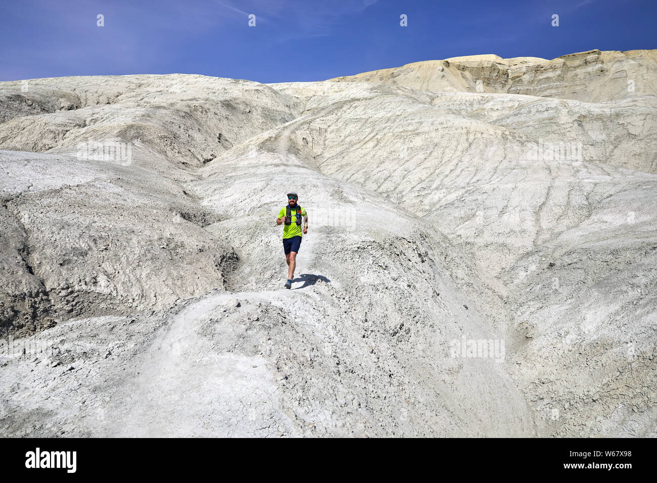 Athlète coureur avec barbe d'exécution sur la piste à l'argile blanche montagne dans le désert Banque D'Images