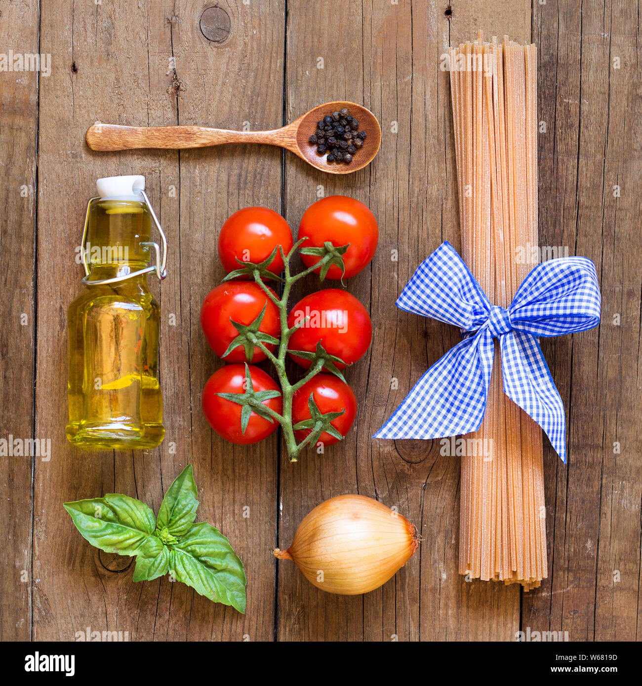 Ingridients pour pâtes avec sauce tomate - tomates, oignons, basilic, huile d'olive vierge extra, poivre et spaghetti de blé entier Banque D'Images