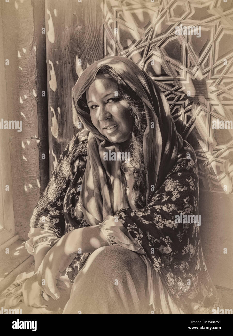 Amira assis à l'ombre des modèles créés par la fenêtre en treillis décoratif les écrans de la mosquée Al-Rifai Banque D'Images