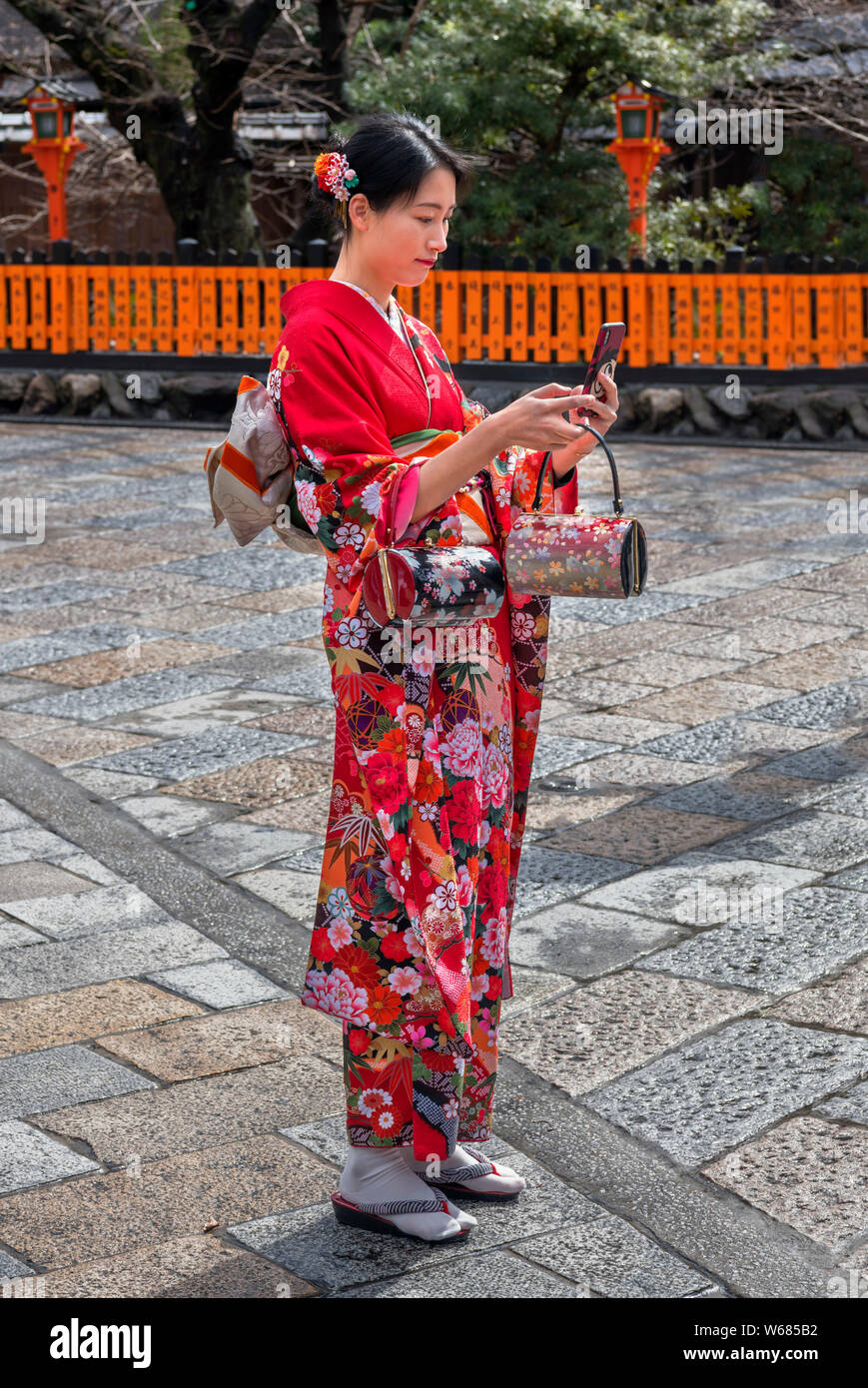 Jeune femme, portant le costume traditionnel, à la recherche de son smartphone, Shinbashi dori, Kyoto, Japon Banque D'Images