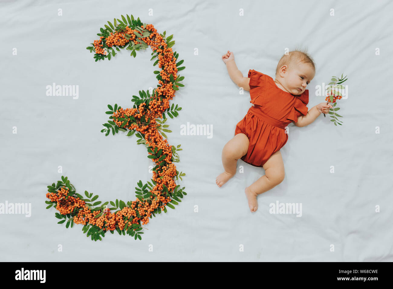 Bebe De Trois Mois Se Coucher Sur Feuille Blanche A Cote Du Numero De Fait Main Hors De Rowan Berries Et Laisse Photo Stock Alamy