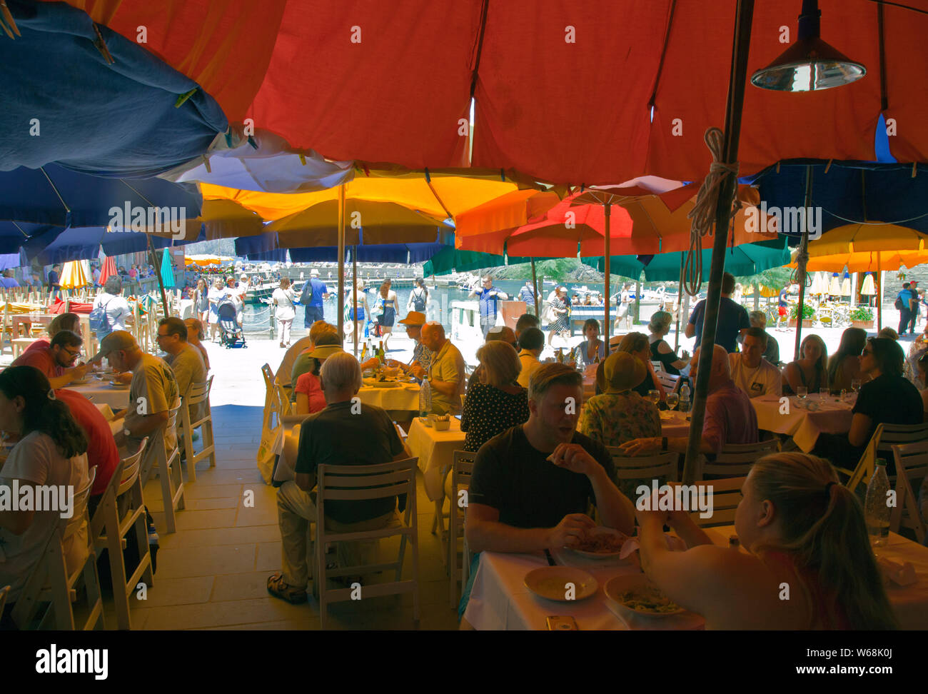 Les personnes mangeant le déjeuner dans un restaurant avant-port à Vernazza, Cinque Terre, Riviera Italienne. Banque D'Images