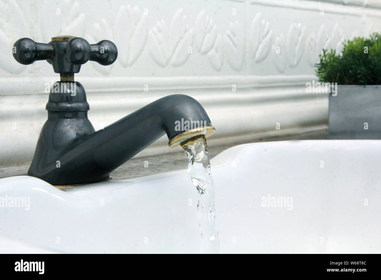 L'eau qui sort du robinet dans l'évier blanc Banque D'Images