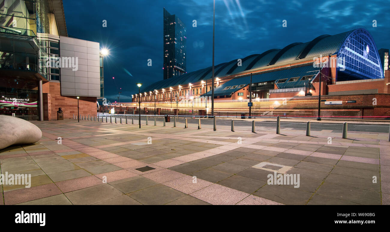 Longue exposition de nuit du tramway passant dans Lower Mosley Street avec Manchester Central, Bridgewater Hall et Beethoam Tower en arrière-plan Banque D'Images