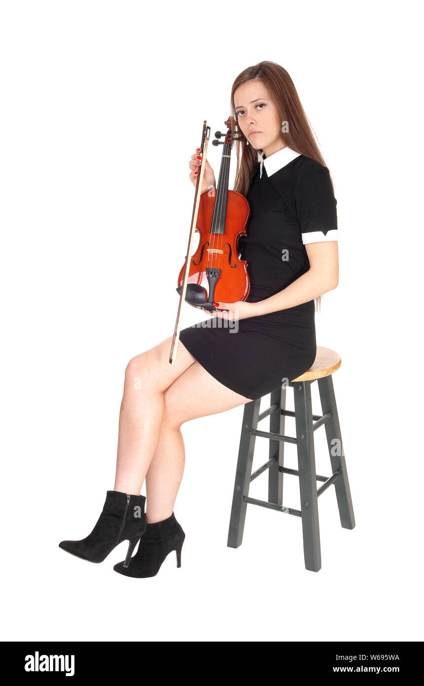 Une belle femme assise dans une robe noire tenant son violon à la recherche de repos dans l'appareil photo, isolée pour fond blanc Banque D'Images