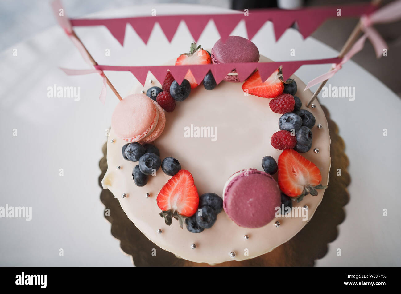 Gateau D Anniversaire Pour Enfants Sur Le Gateau Il Y A Des Baies De Framboises Bleuets Et Fraises Violet Et Rose Macarons Drapeaux Et Rose Decoration Photo Stock Alamy