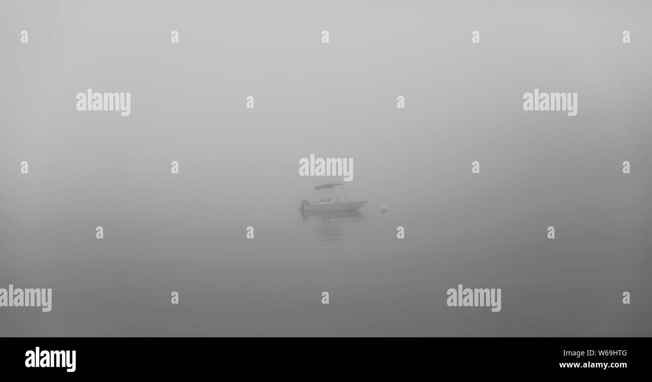 Un petit bateau dans la distance d'un matin brumeux brumeux au large de la côte du Maine Banque D'Images