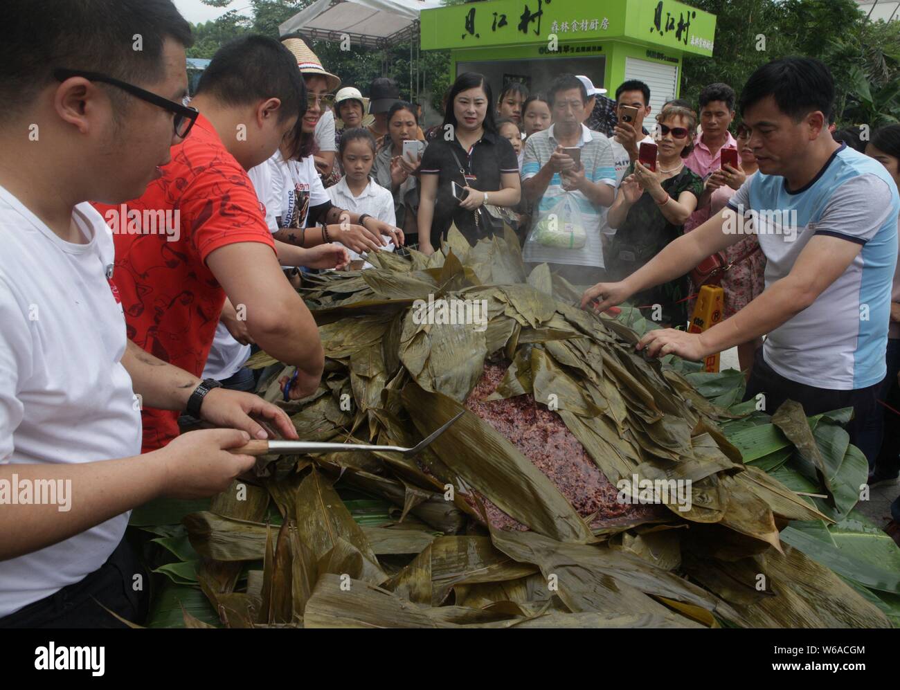 Les citoyens partagent un énorme zongzi, une boulette en forme de pyramide fait de riz gluant enveloppé dans des feuilles de roseau ou de bambou dans la ville de Liuzhou, Guangxi en Chine du sud Banque D'Images