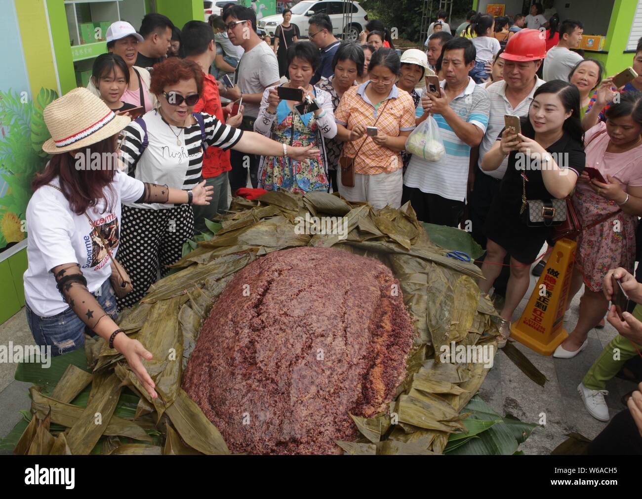 Les citoyens partagent un énorme zongzi, une boulette en forme de pyramide fait de riz gluant enveloppé dans des feuilles de roseau ou de bambou dans la ville de Liuzhou, Guangxi en Chine du sud Banque D'Images