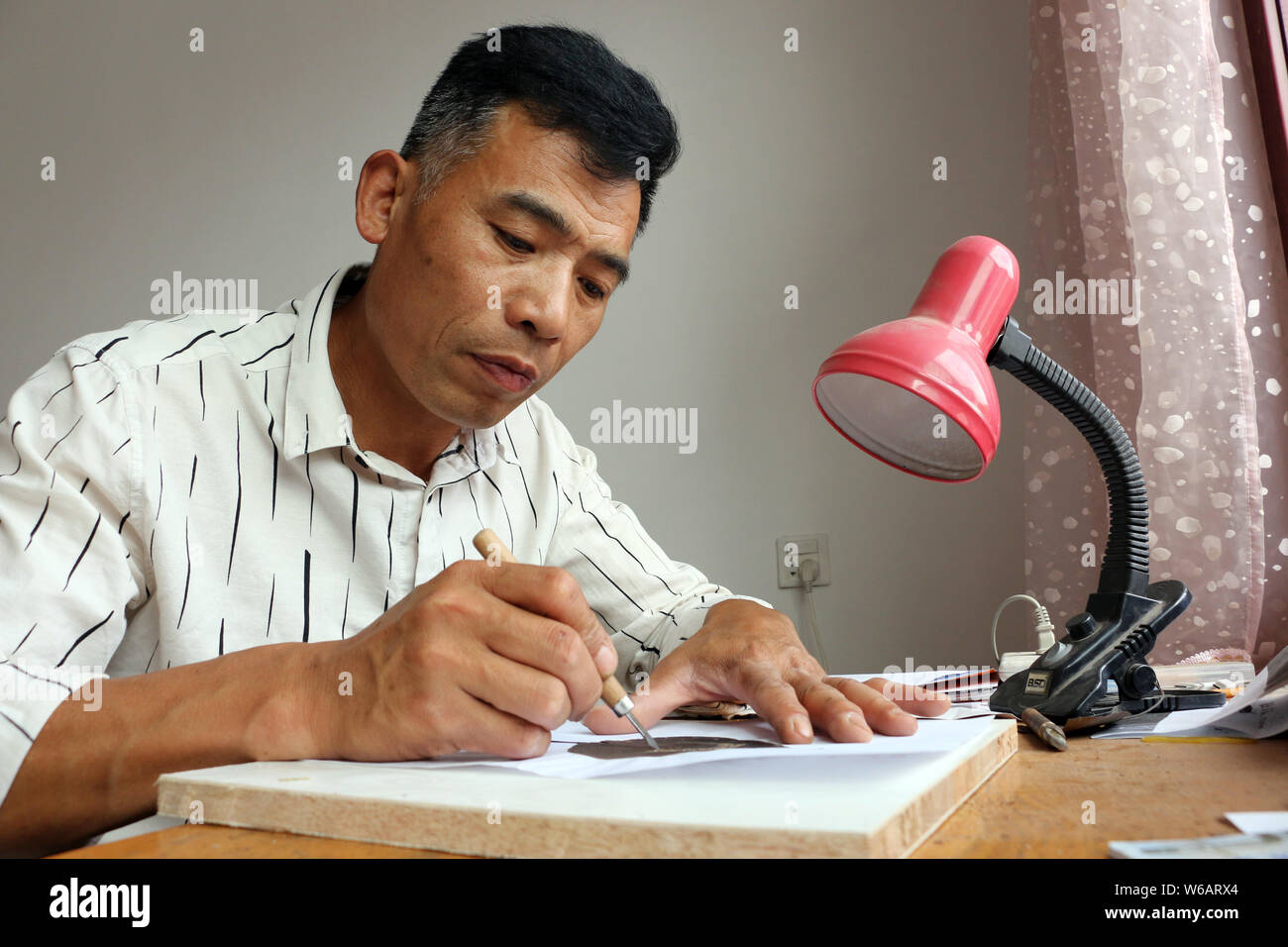 Artisan chinois Kong Qingsi sculpte une feuille traitée dans son QR code de l'application messagerie Weixin, ou WeChat, de Tencent en ville Shiqiang, Zoucheng c Banque D'Images