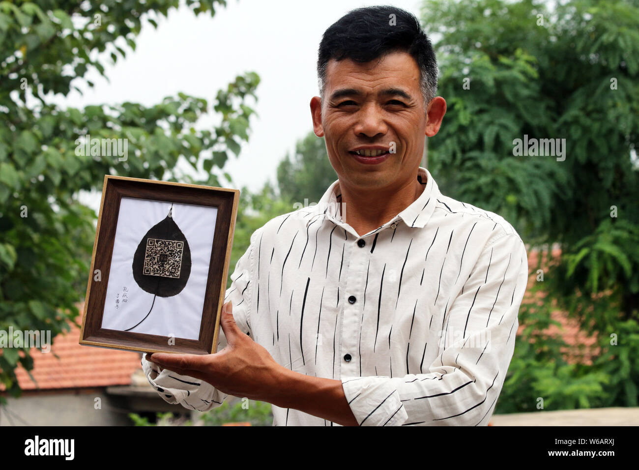 Artisan chinois Kong Qingsi montre une feuille traitée avec son QR code de l'application messagerie Weixin, ou WeChat, de Tencent sculpté par lui-même sur elle en Sh Banque D'Images