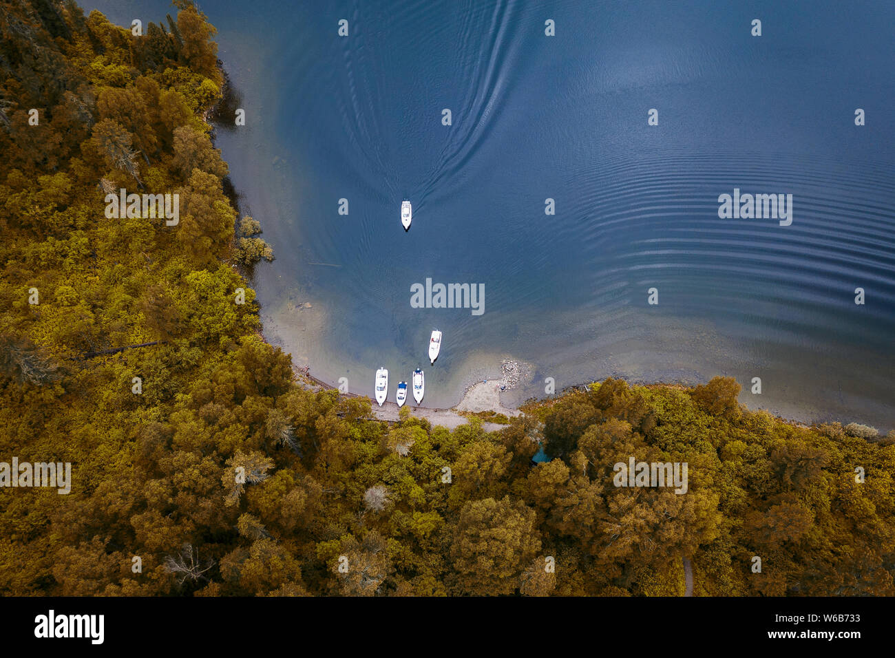 Vue aérienne du lac avec bateaux près de la côte et un bateau à l'embarcadère avec orange et jaune des arbres sur l'été indien. Banque D'Images
