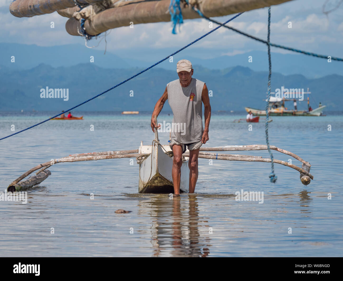 Sarangani, Philippines - Le 9 juillet 2017 : vieux pêcheur prenant son petit bateau outrigger au rivage à Maasim, dans la province de Sarangani Philipp Banque D'Images