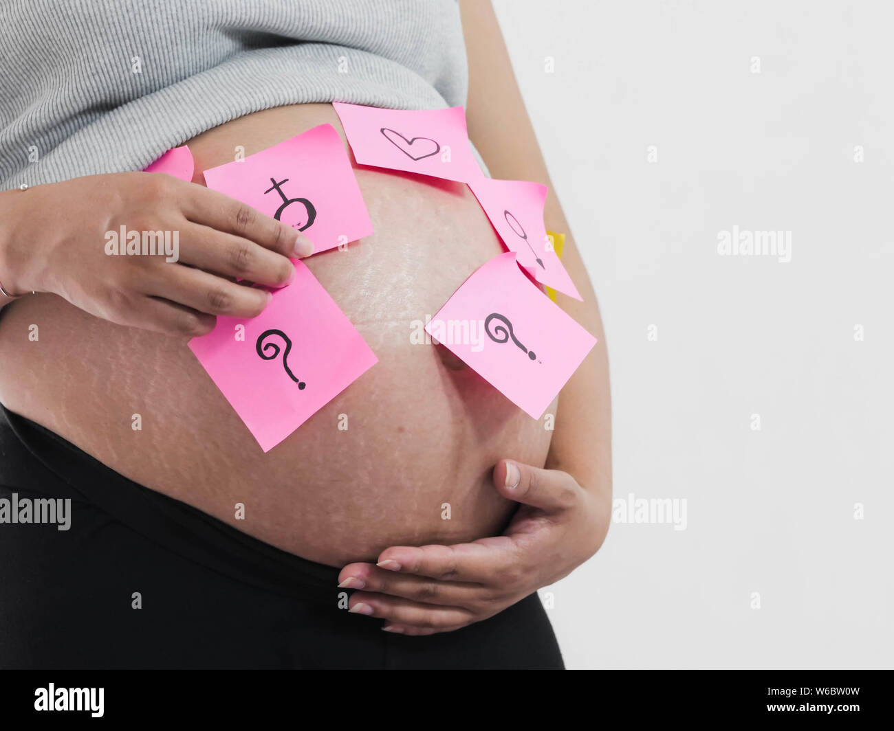 Partie du corps pregnant belly avec post-it rose sur fond blanc. Banque D'Images