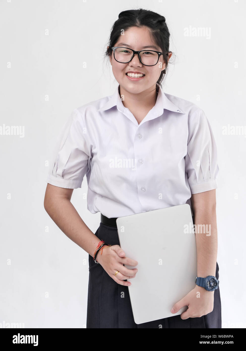 Heureux étudiant asiatique en uniforme holding laptop sur fond blanc. Banque D'Images