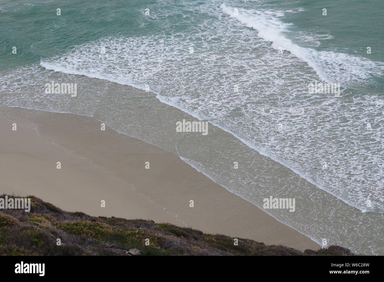 Regardant vers le bas de la falaise, sur des vagues d'une mer turquoise à Chapel Plage de Porth. Cornwall, UK. Banque D'Images